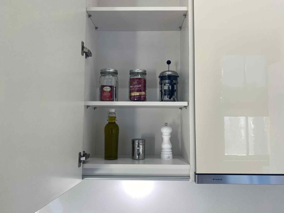 Kitchen cupboard stocked with tea, coffee, and oil